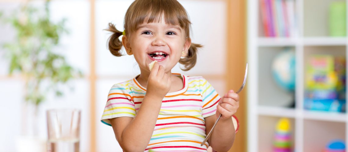 46063451 - happy kid girl eating healthy food vegetables at home